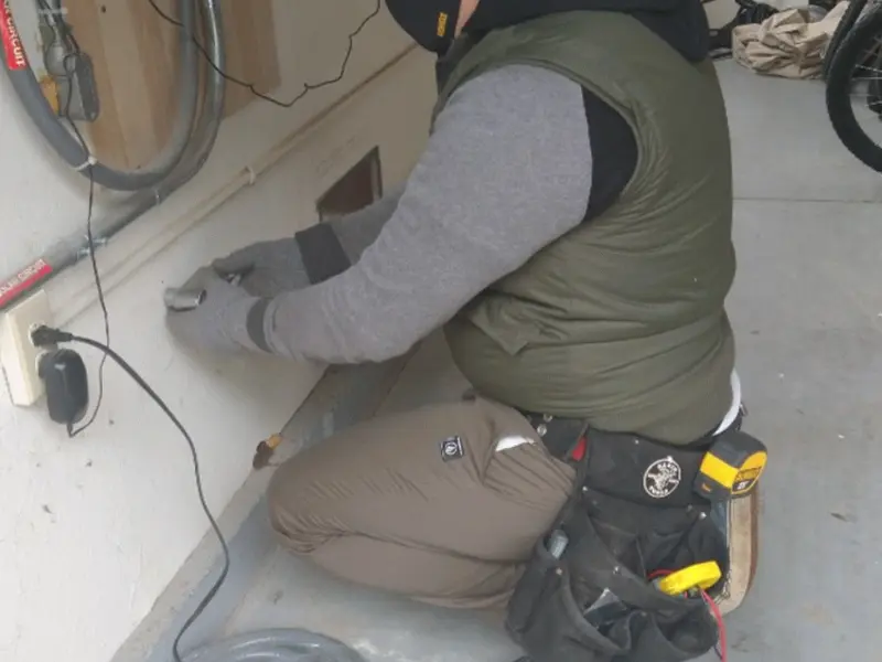 Electrician performing outlet wiring in a Crowley garage